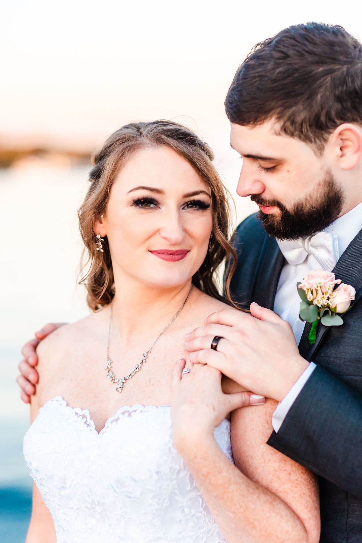 Romantic sunset portrait of a couple showing off wedding rings and jewelry.
