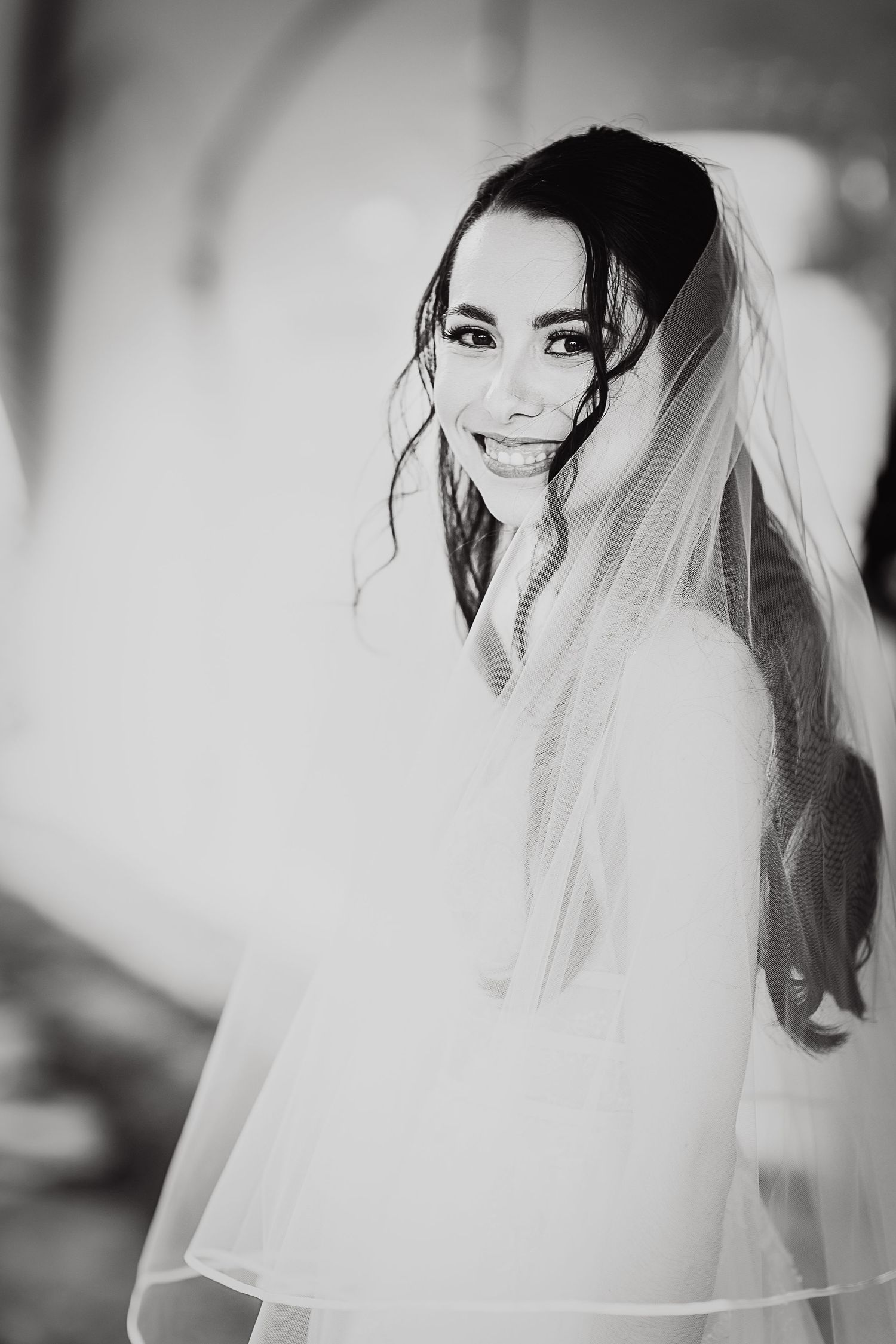 A black and white portrait of a bride wearing a flowing veil.