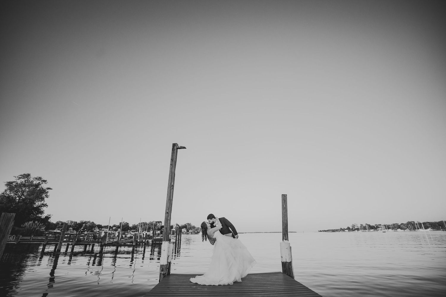 A black and white romantic moment captured between newlyweds on a dock.
