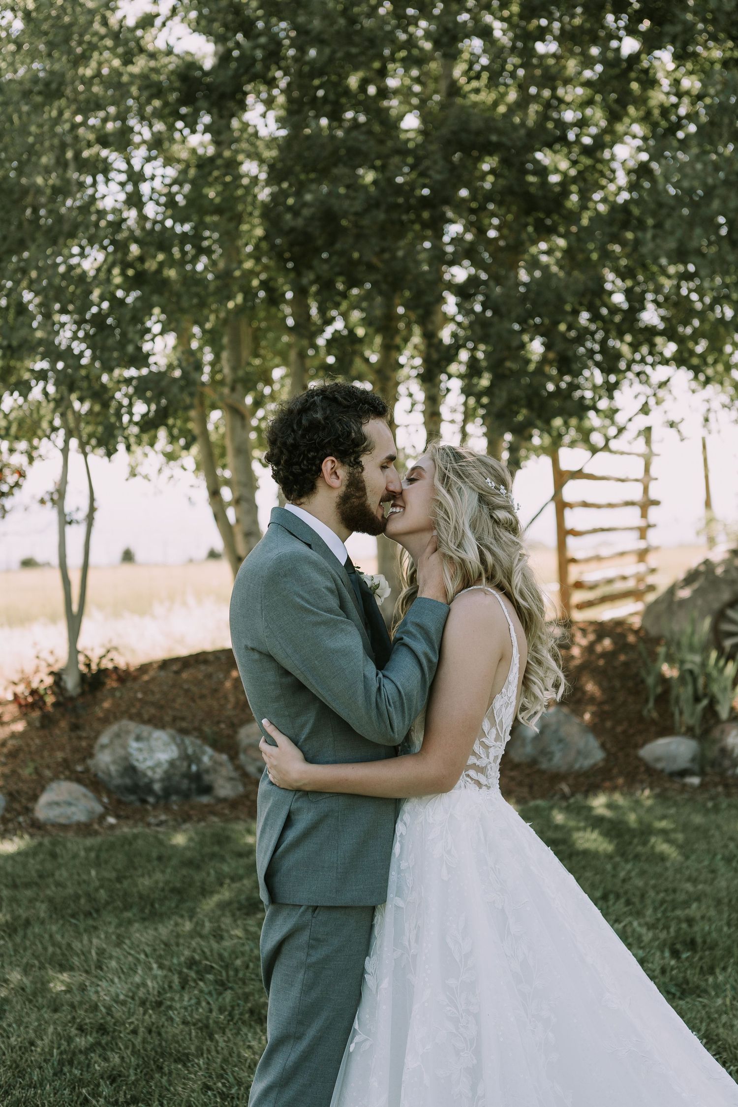 Tender moment between newlyweds as they embrace for a kiss in an outdoor setting.