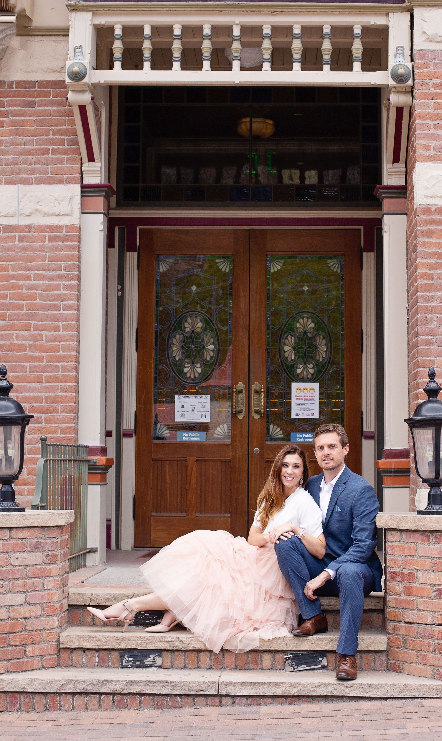 Couple sitting romantically on steps of historic hotel entrance.