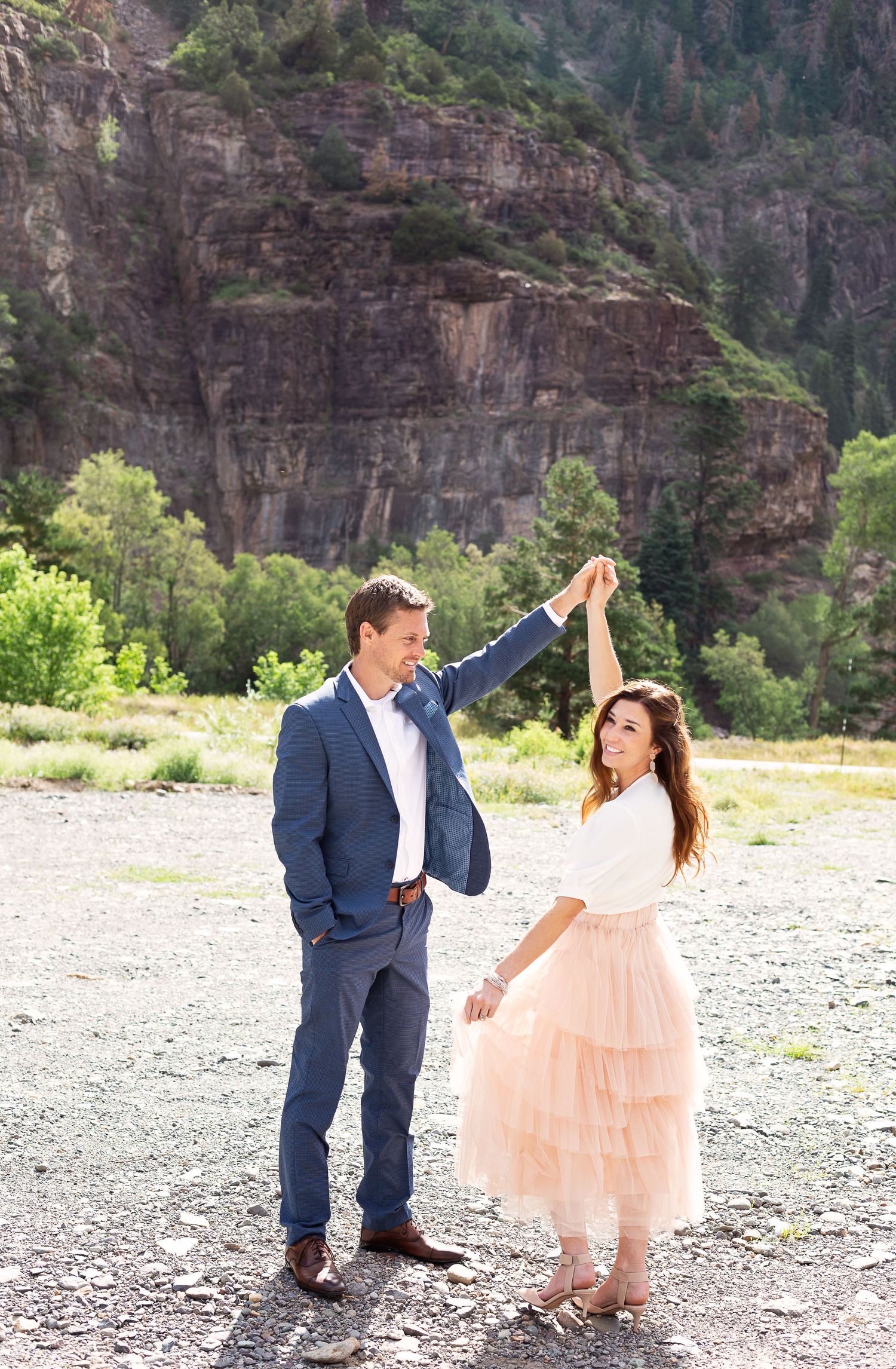 A couple dancing together in front of towering canyon cliffs.