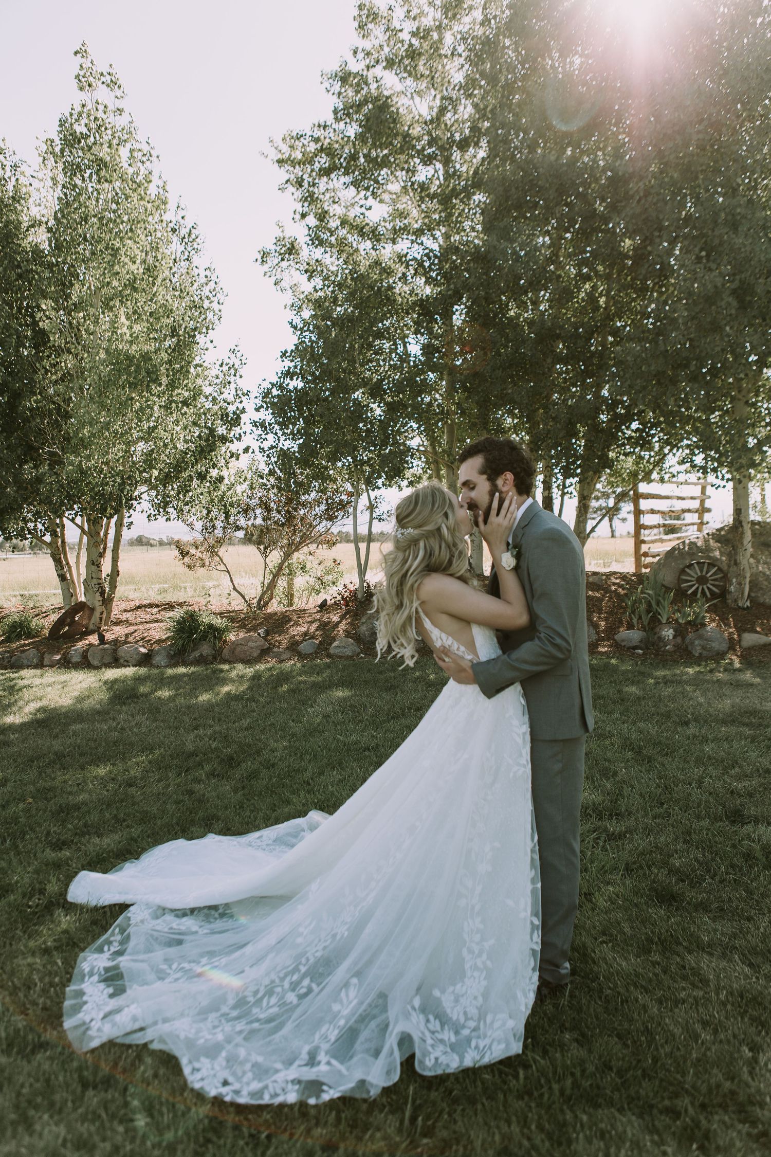 Romantic wedding moment captured in garden setting with flowing lace gown catching breeze.