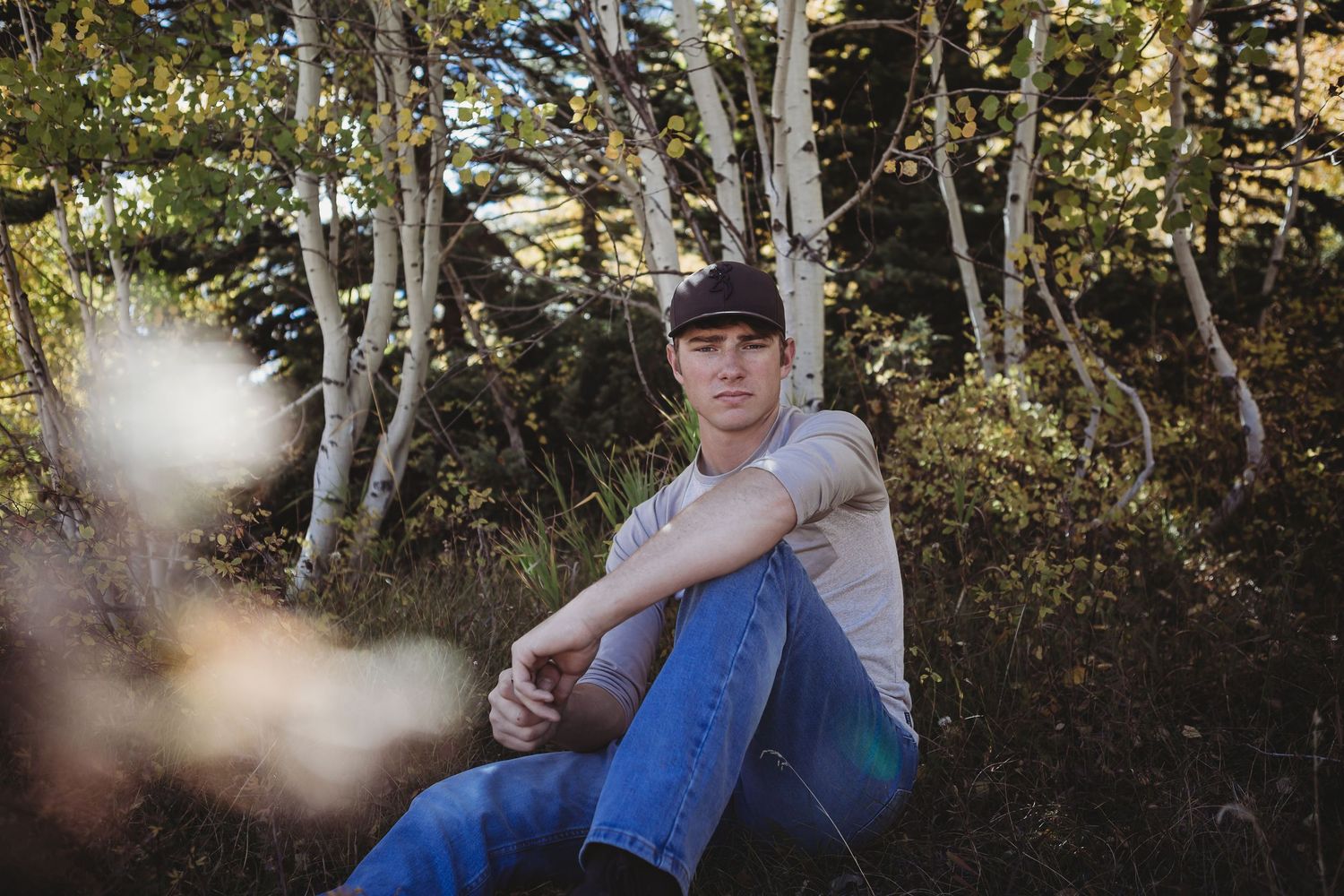 Casual outdoor portrait among birch trees in dappled sunlight.