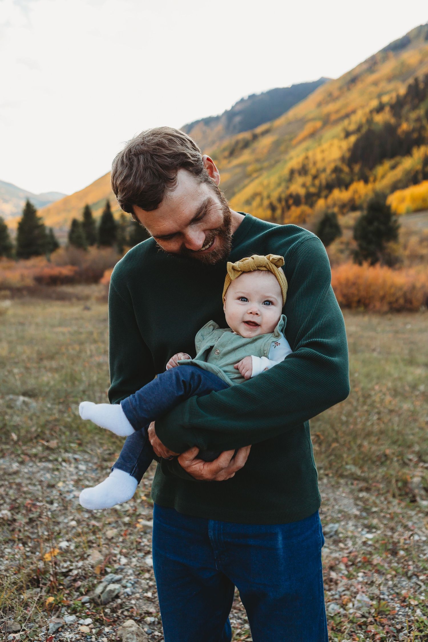 Tender moment between parent and baby against mountain backdrop.
