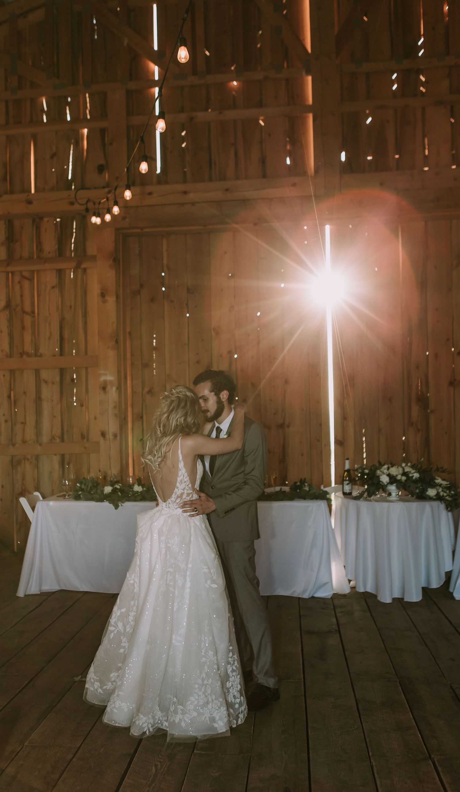 Couple sharing an intimate dance in a rustic barn with magical light streaming through.