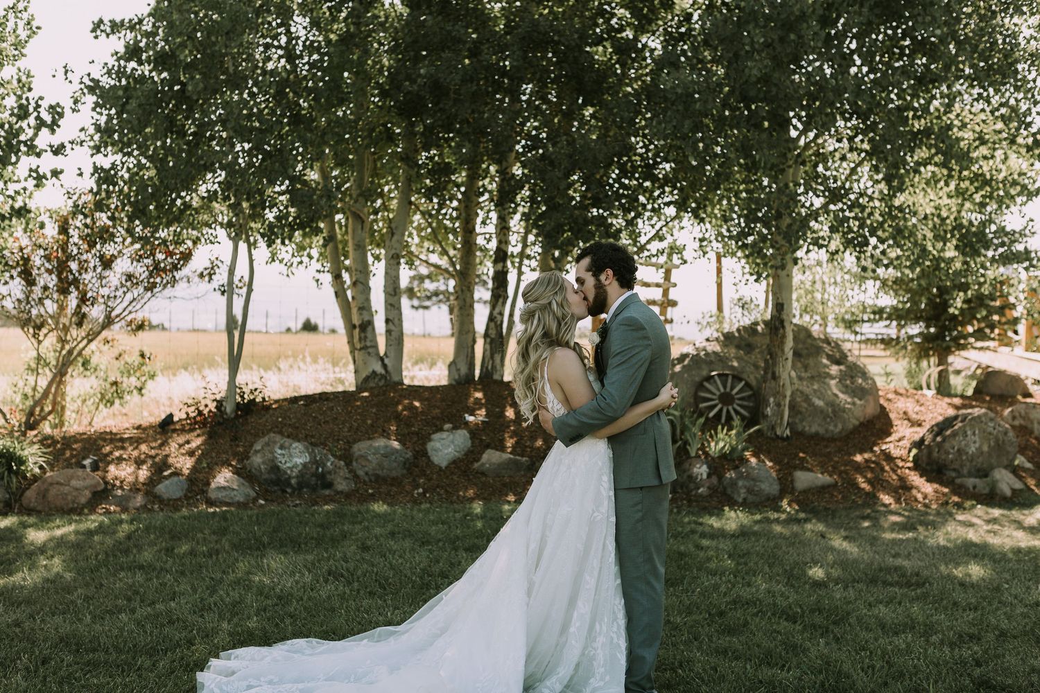 A playful wedding portrait with the bride's dress billowing in the breeze among trees.