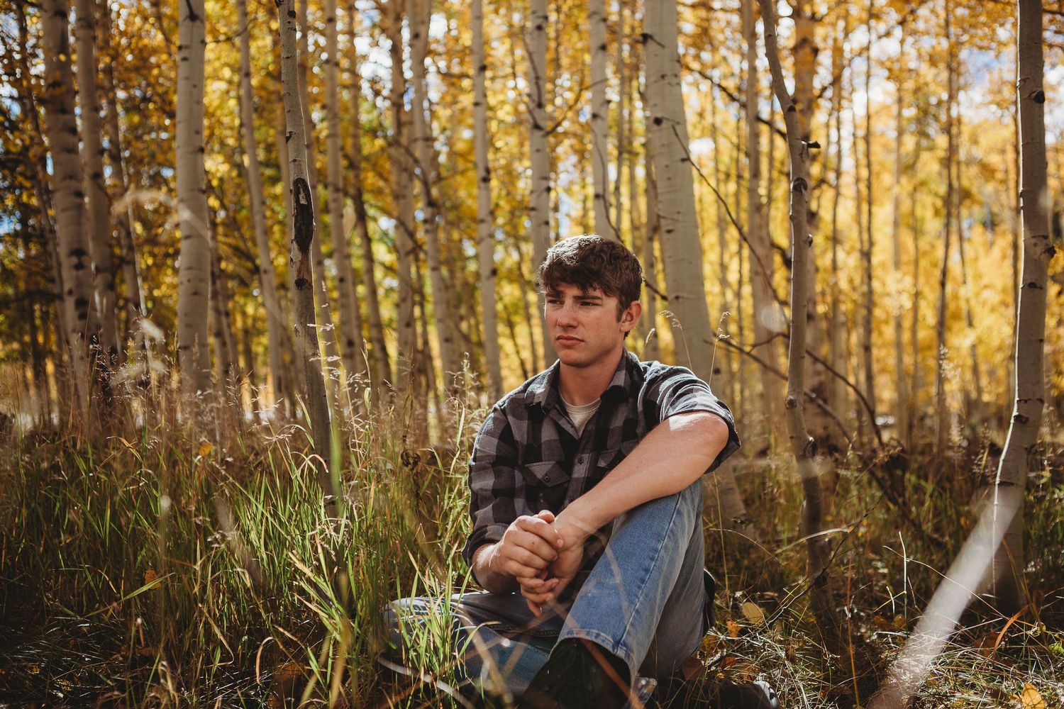 Outdoor portrait among golden aspen trees during autumn season.