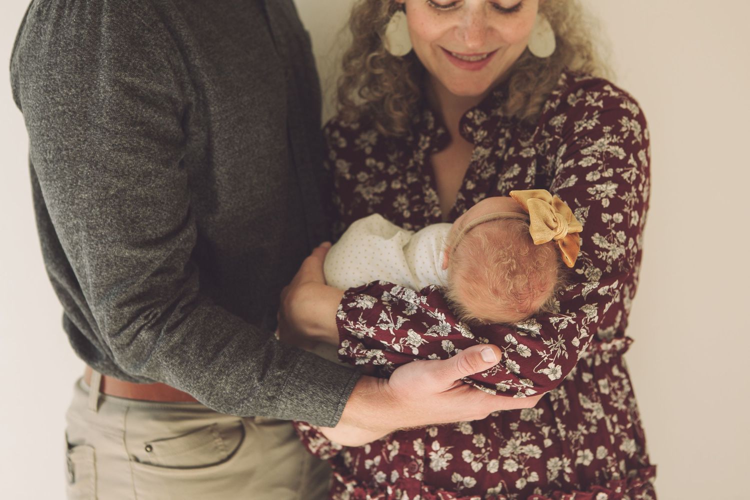 Parents in casual wear gazing lovingly at their swaddled newborn.
