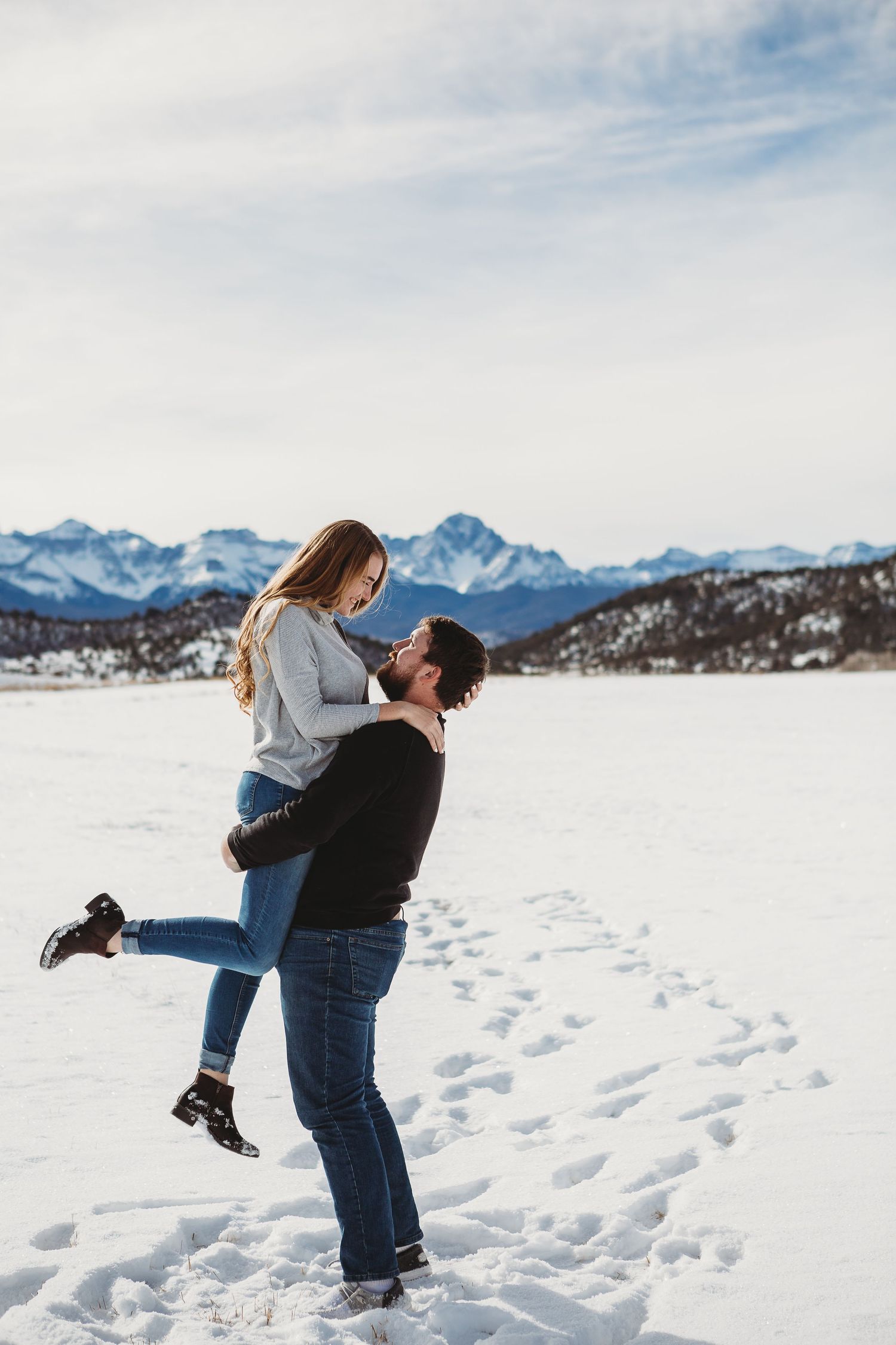 Joyful lift pose in a snowy mountain landscape.