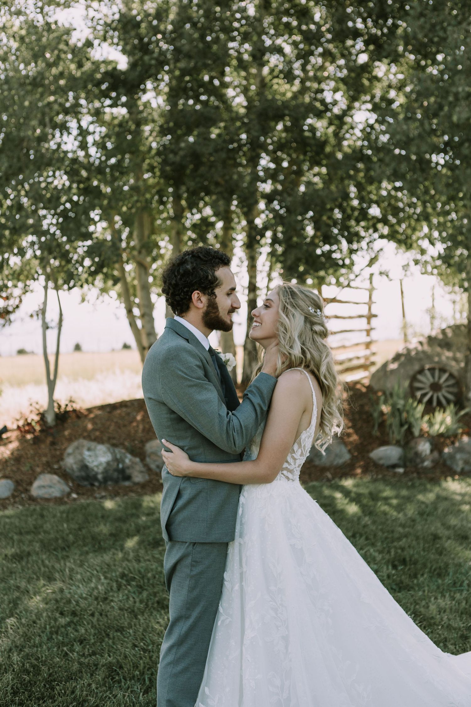 A tender embrace between newlyweds surrounded by lush trees and greenery.