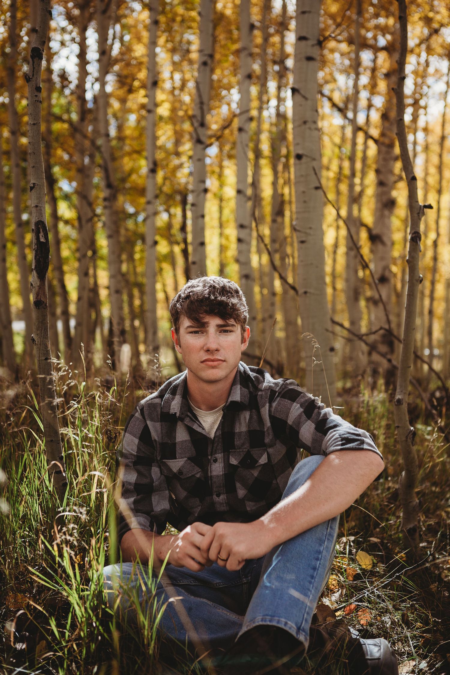A casual portrait in a sunlit aspen forest with fall foliage.