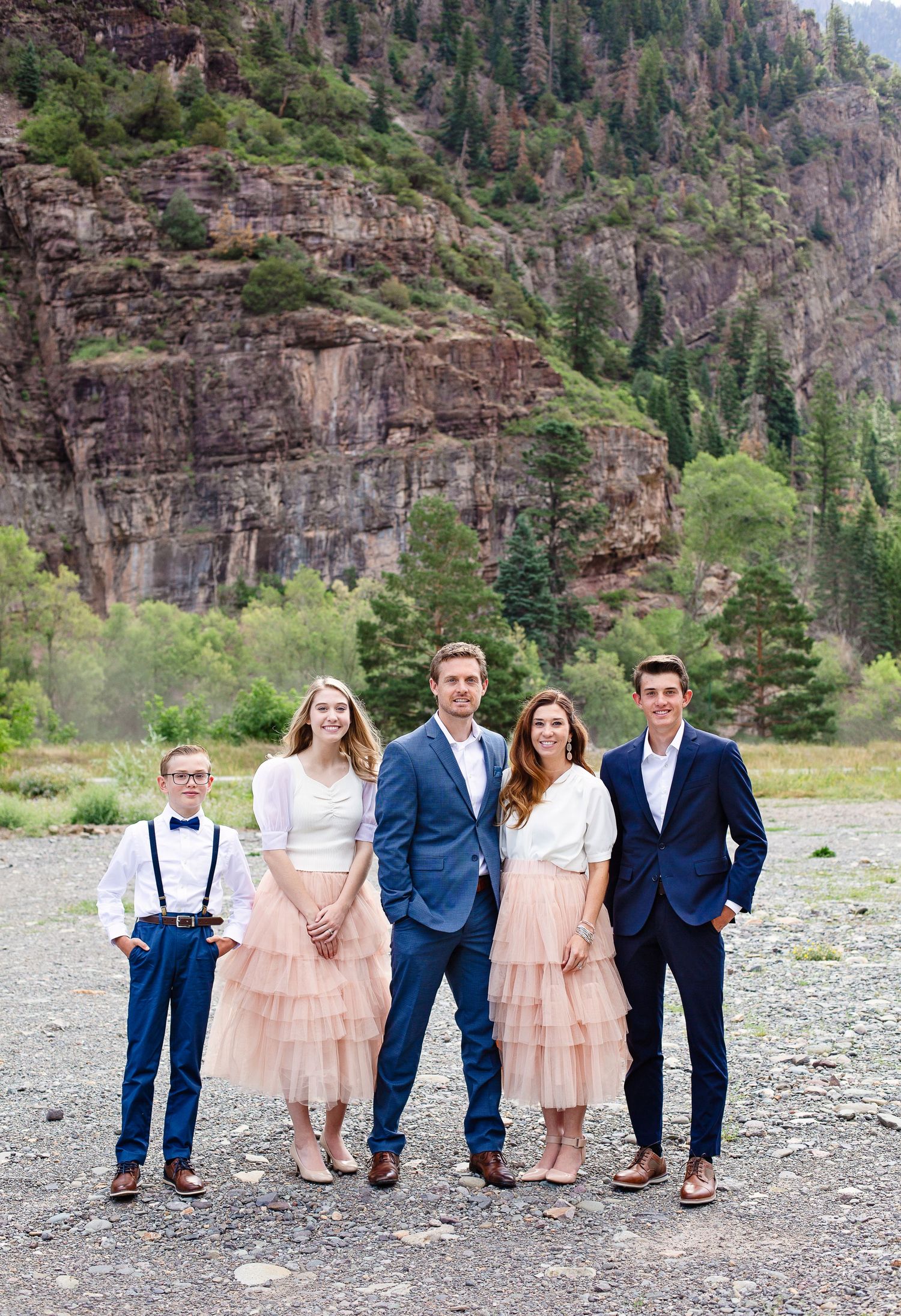 A group posed in formal attire against a dramatic rocky canyon backdrop.