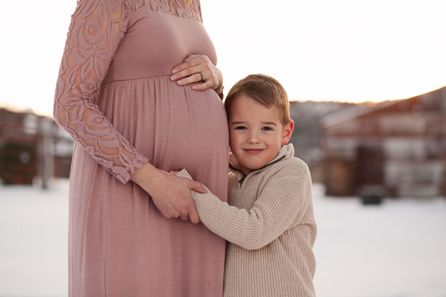 Sweet interaction between child and expecting mother in winter setting.