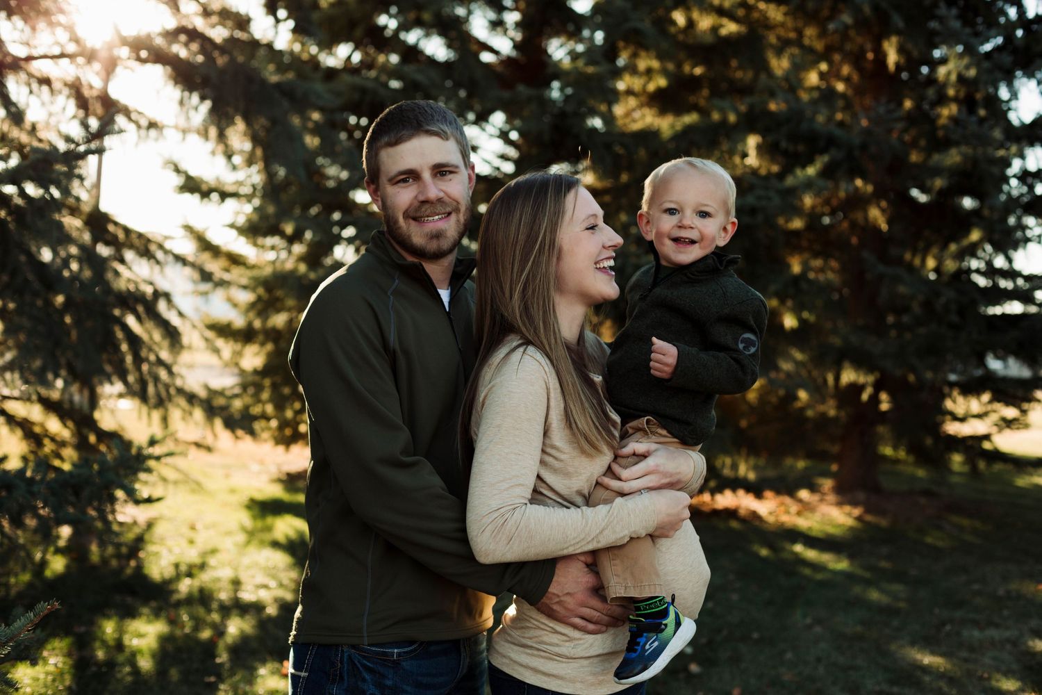 Candid family moment shows joyful interaction between parents and child during outdoor photoshoot.