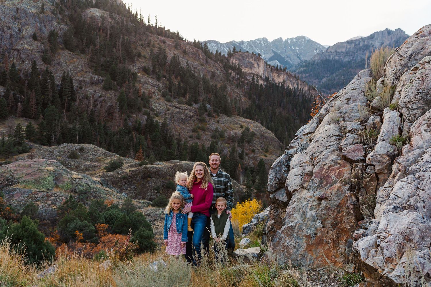 Fall mountain landscape with people gathered by large rock formations in a scenic valley.