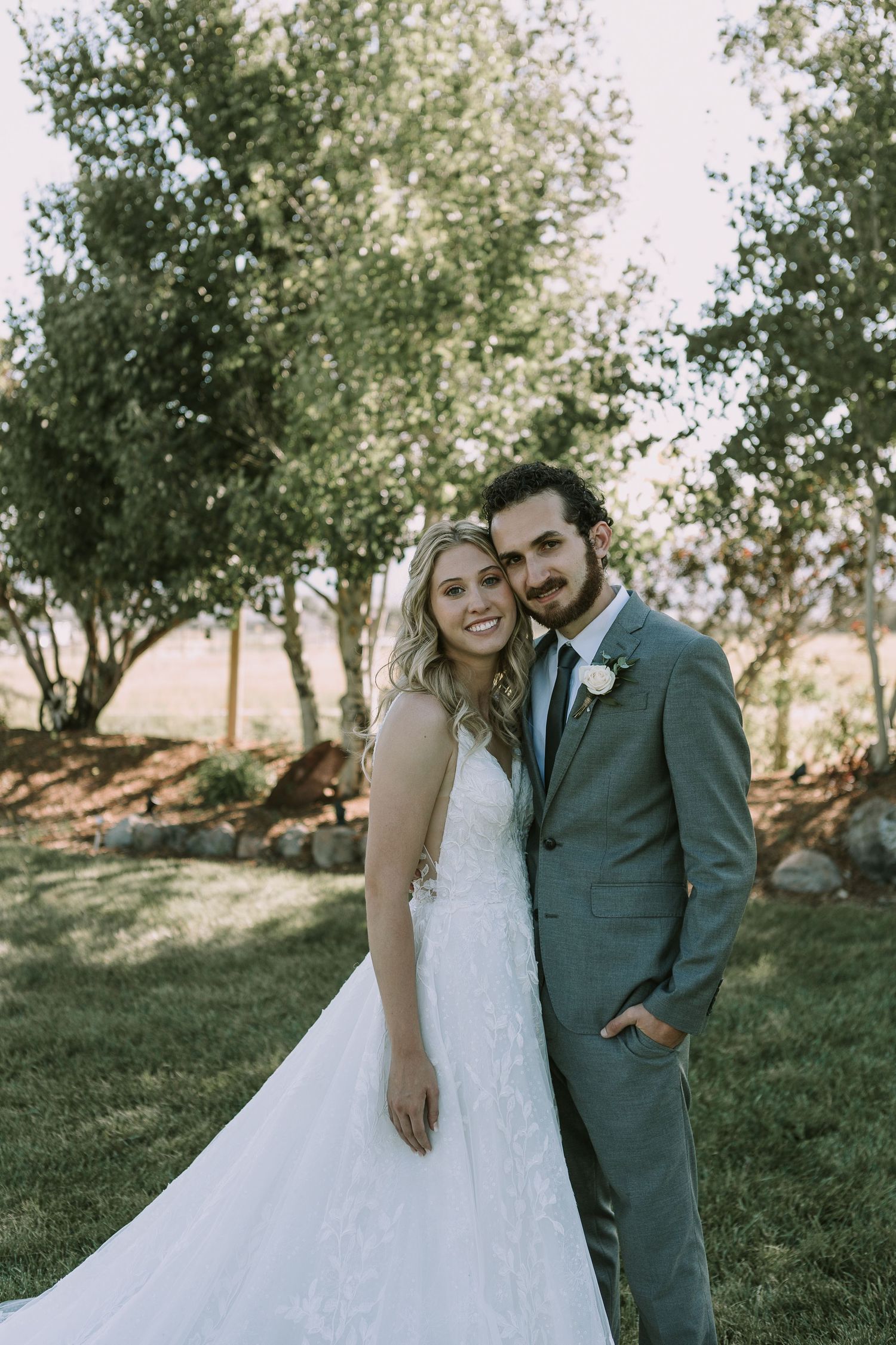 Newlyweds share joyful moment together in outdoor garden setting wearing elegant wedding attire.