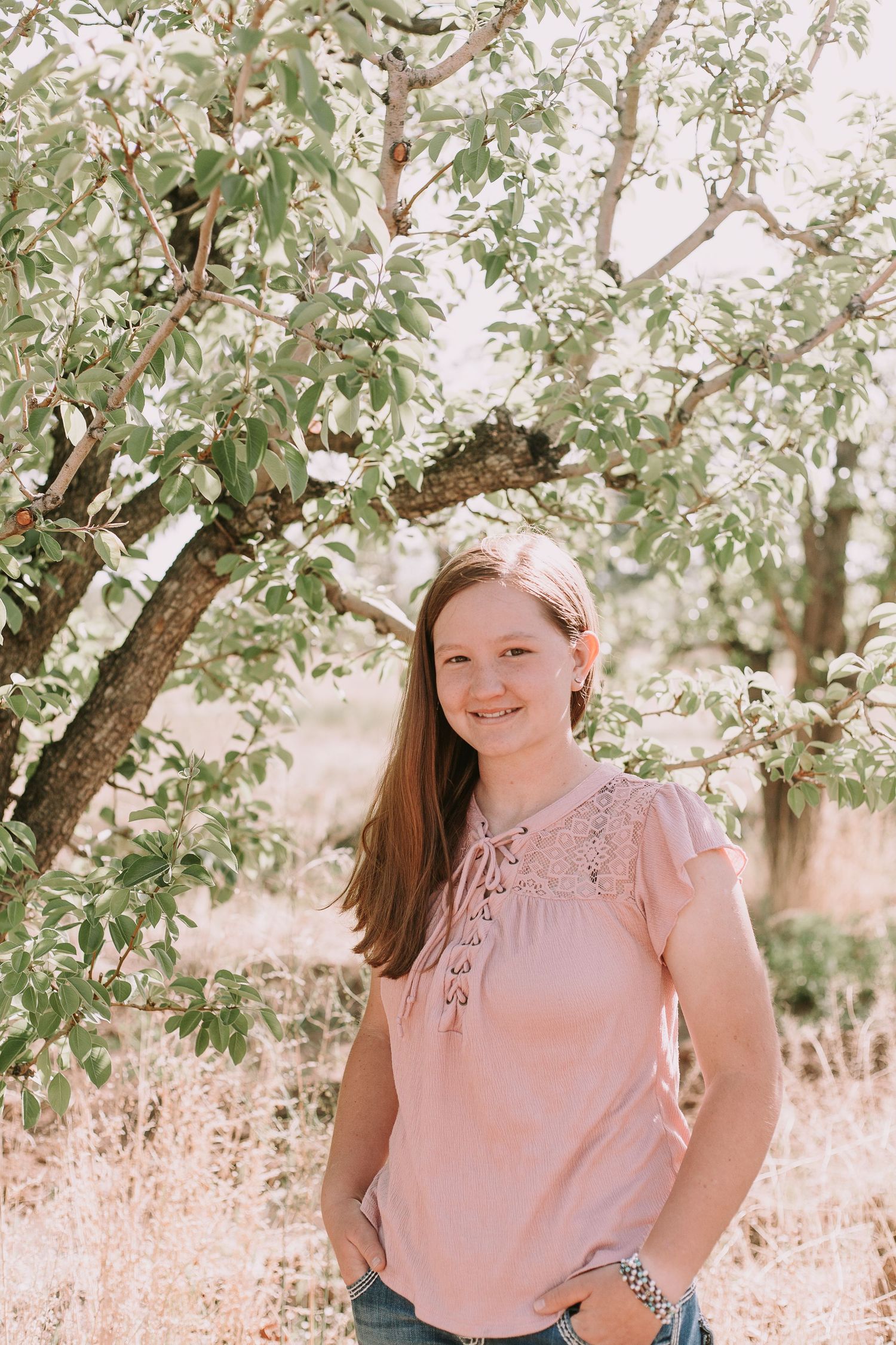 A casual outdoor portrait under a flowering tree with soft sunlit background.