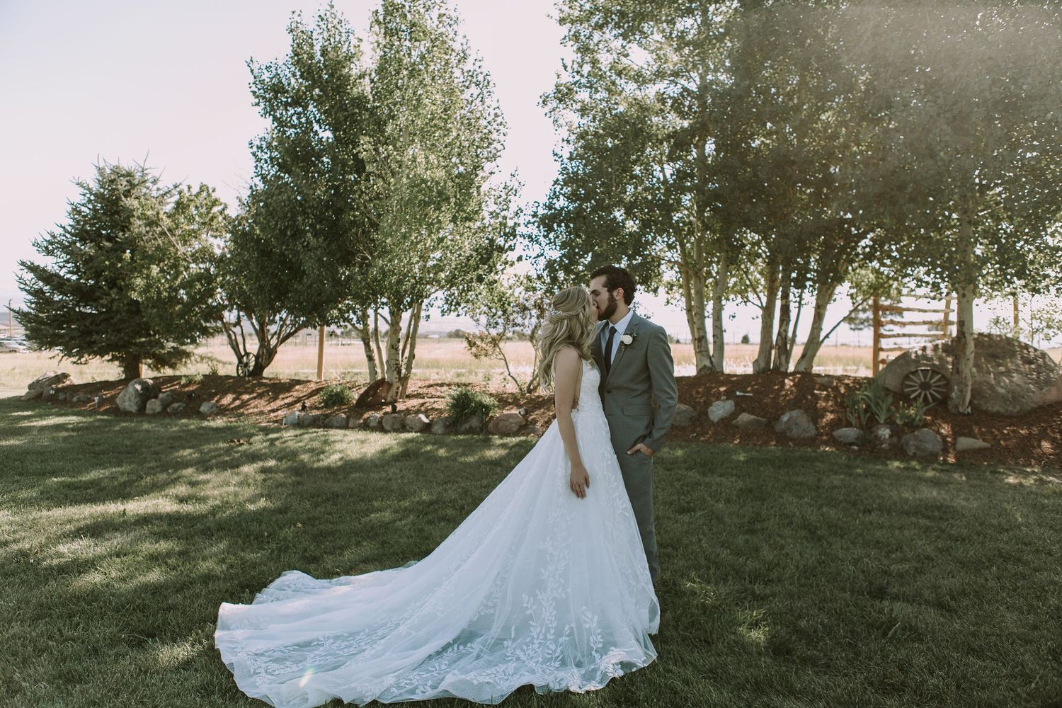 Wedding couple stands in outdoor garden setting with dramatic cathedral length dress train.