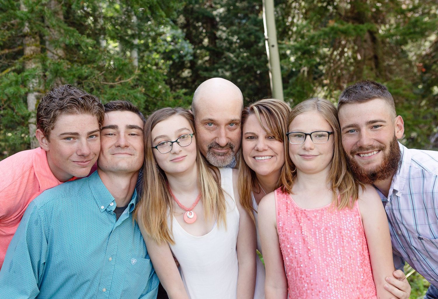 A casual group portrait taken outdoors with green foliage in the background.