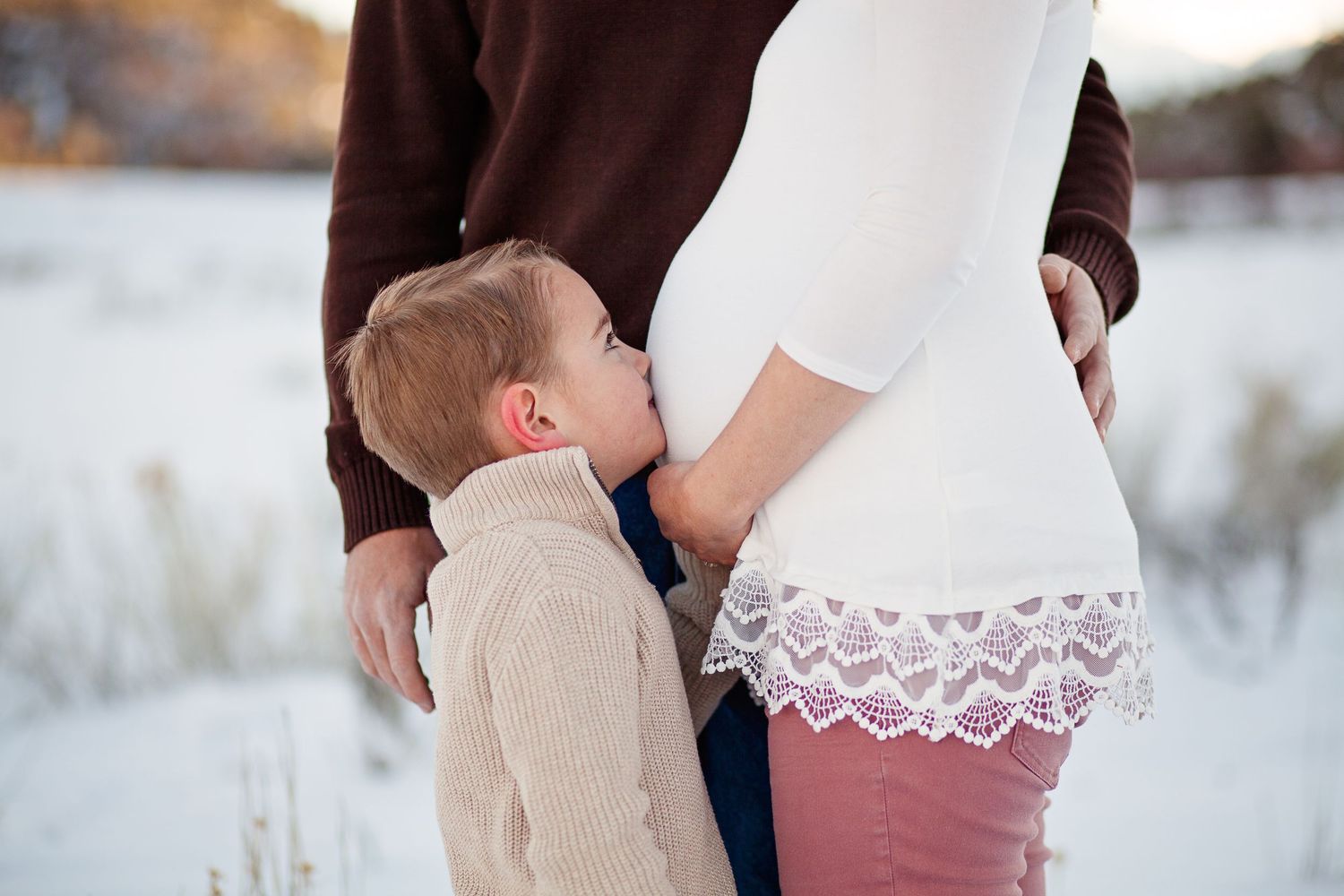 Close-up shot of maternity moment in snowy outdoor setting.