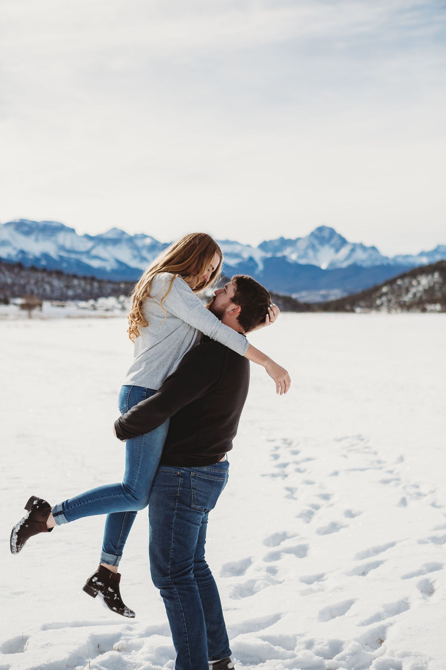 A romantic winter embrace against snowy mountain backdrop.