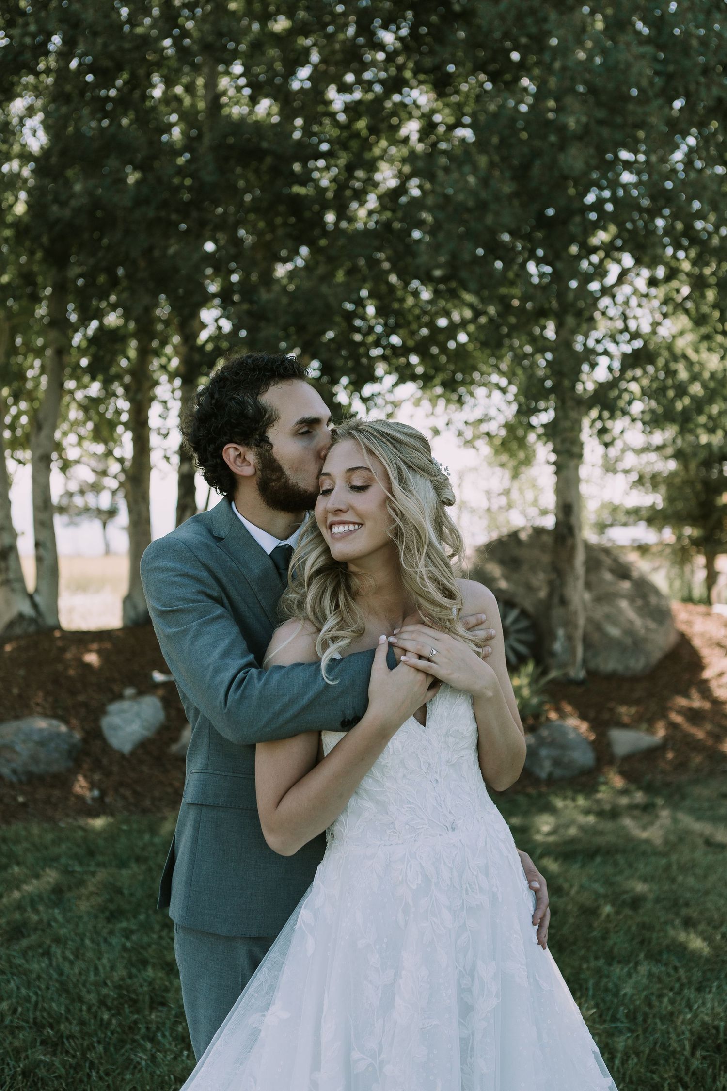 Romantic embrace between newlyweds sharing a joyful moment in an outdoor garden setting.