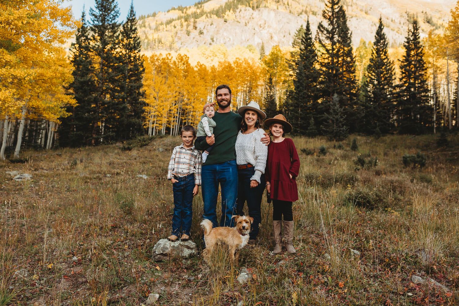 Family with children and dog pose for portrait in fall mountain setting.
