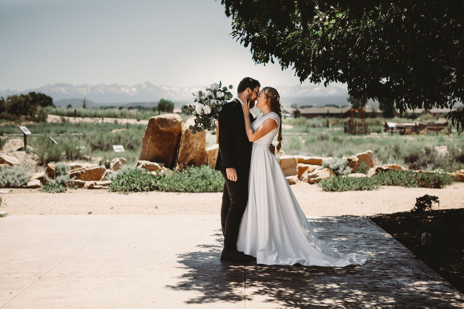 A romantic wedding moment captured outdoors with mountains and natural scenery in the background.