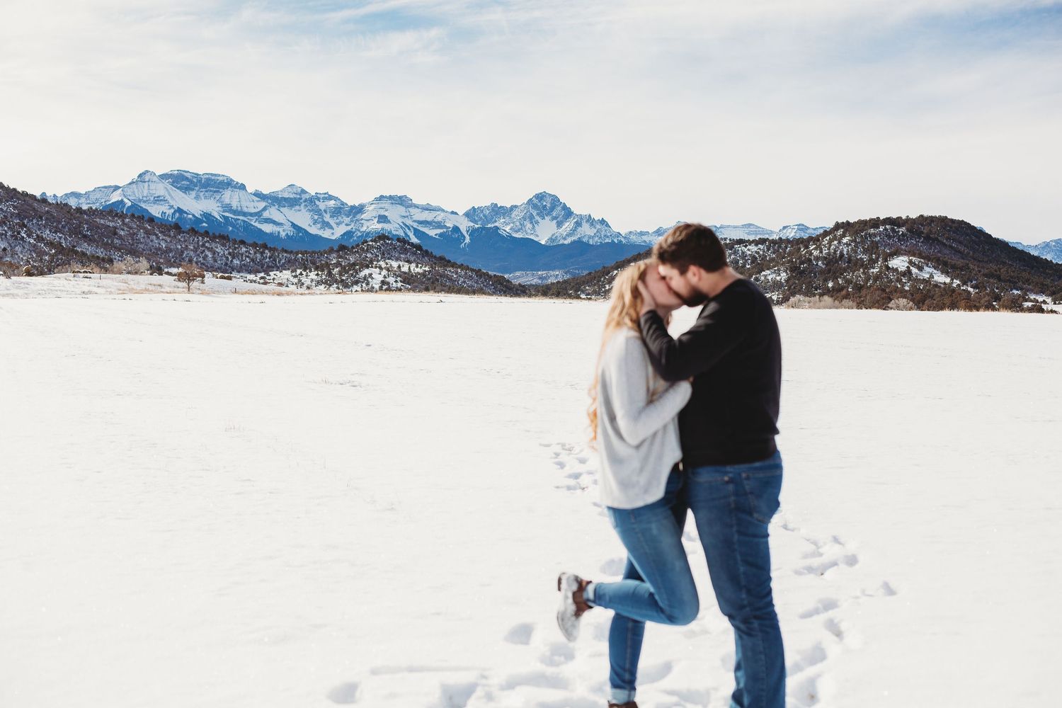 A playful winter moment captured in a snowy landscape with mountains in the distance.