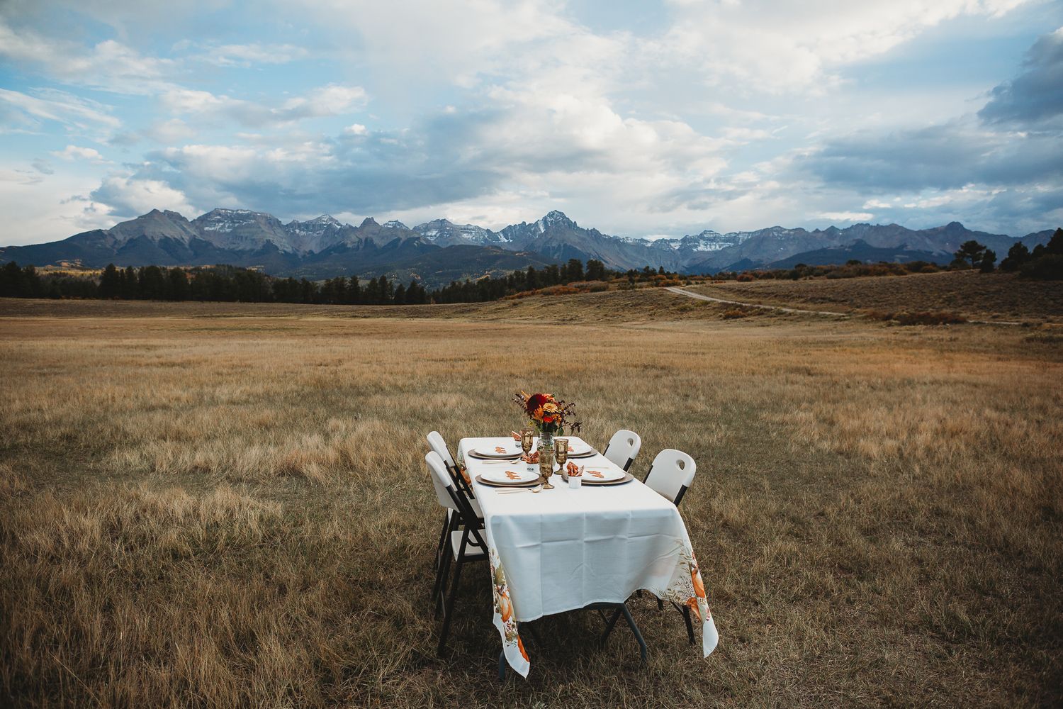 An elegant table setting with white linens against a dramatic mountain landscape.