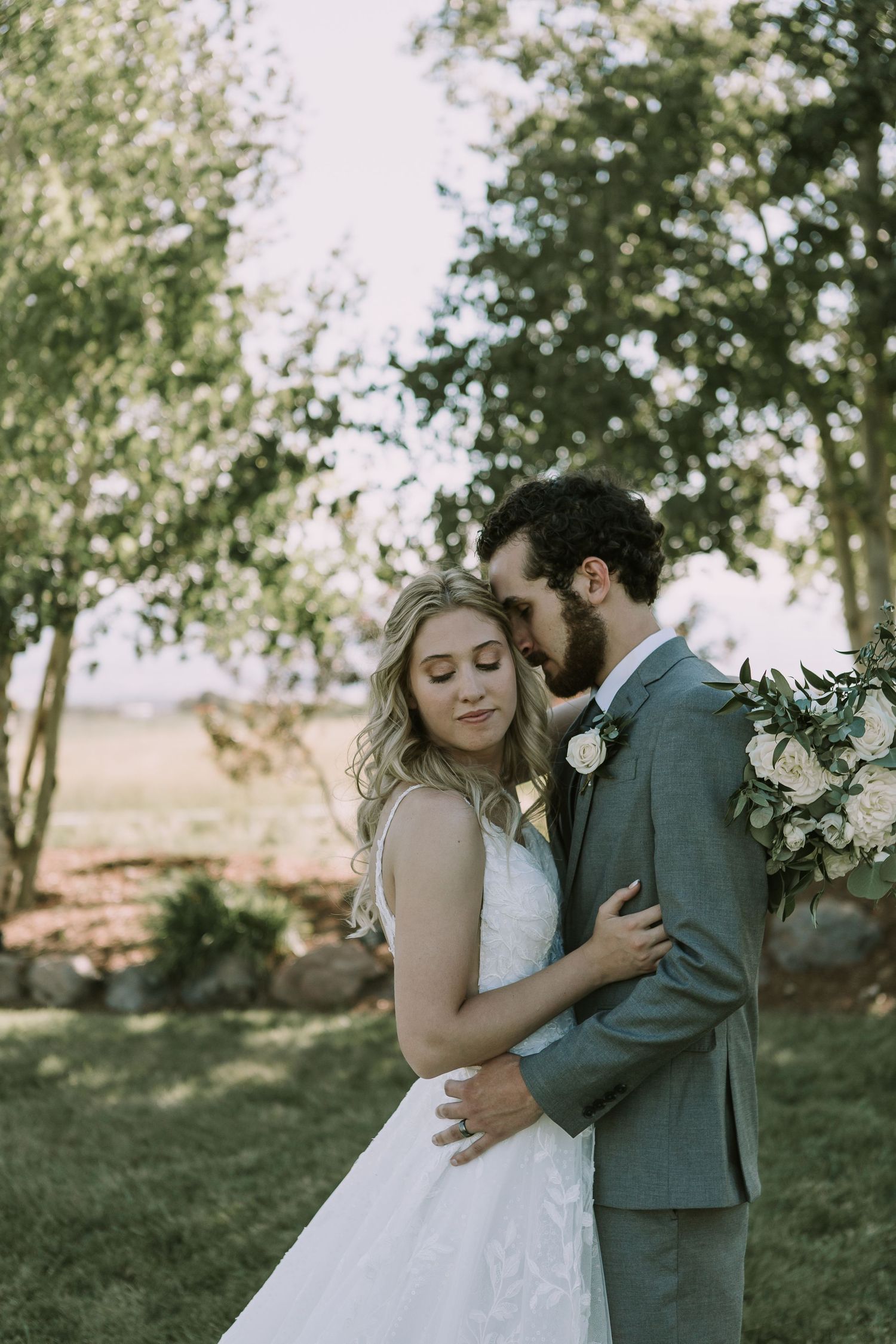 A couple shares an intimate moment on their wedding day in a garden setting with soft natural lighting.