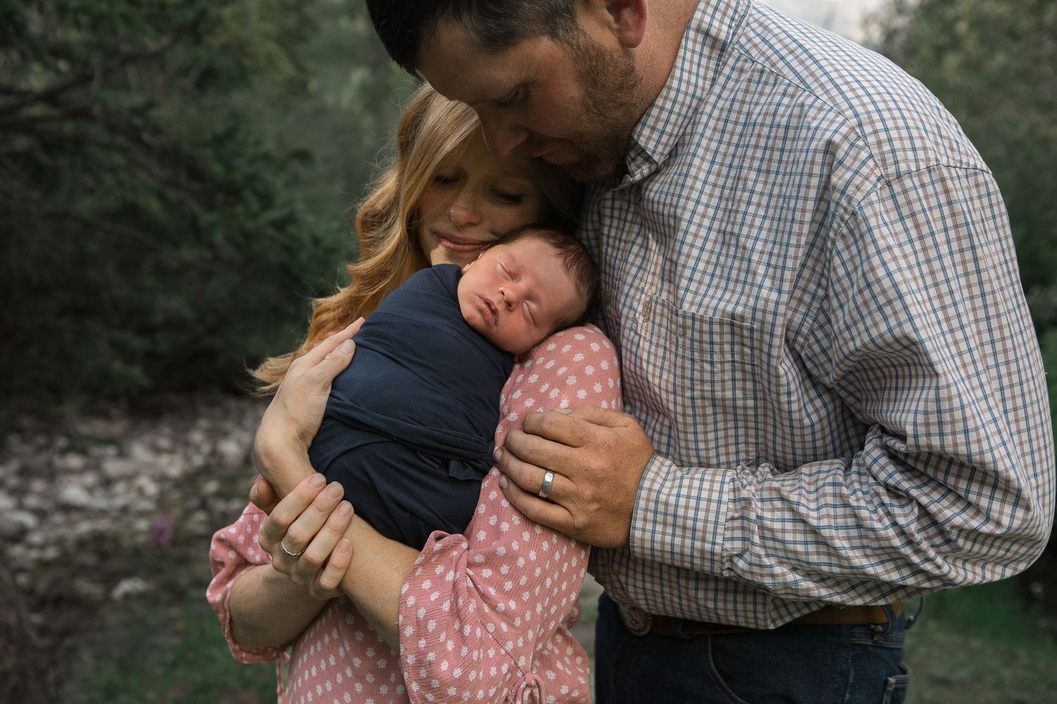 Close-up of gentle embrace with infant amongst mountain scenery.