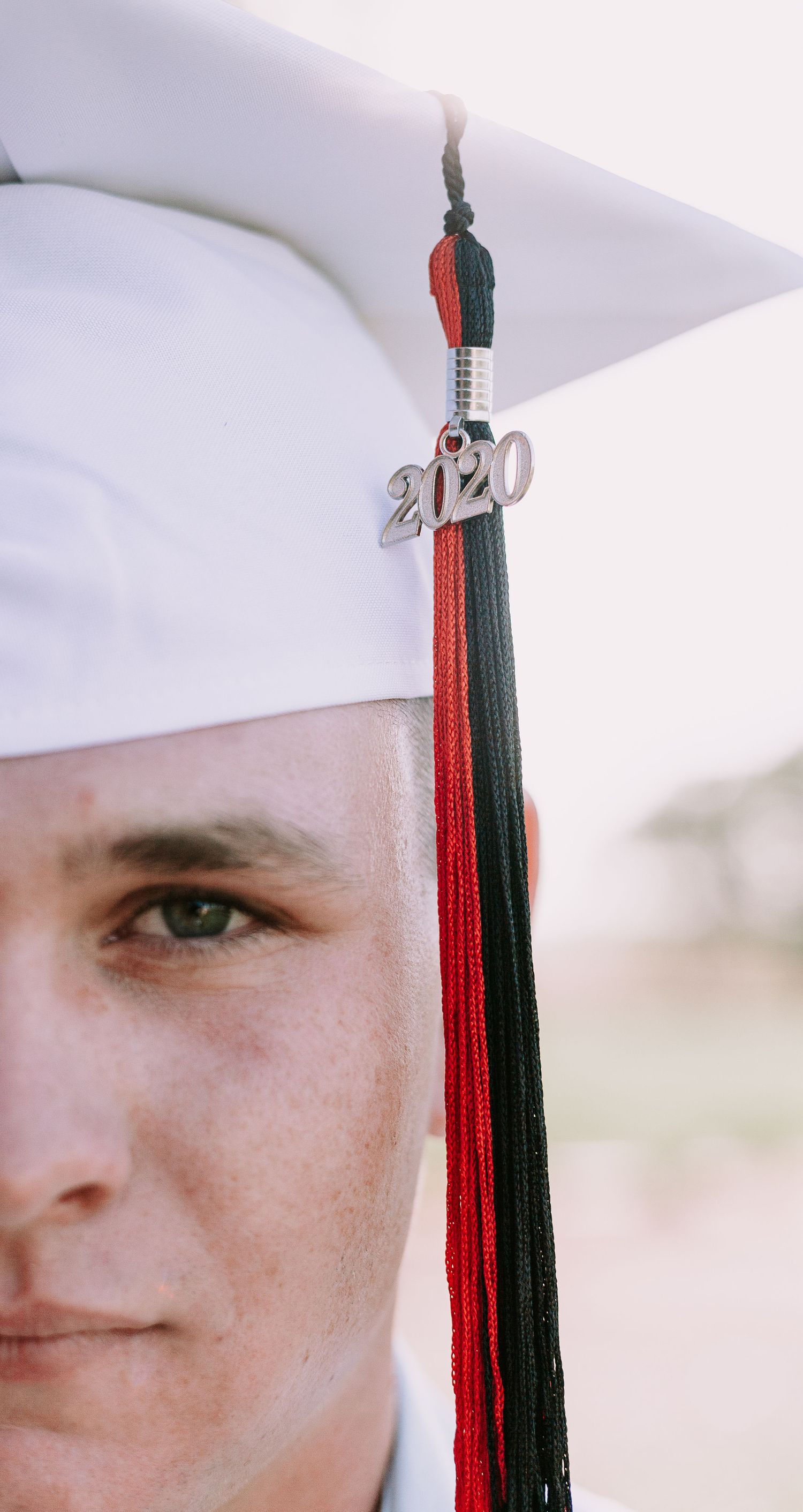 Close-up of graduation cap tassel with 2020 charm against white background.