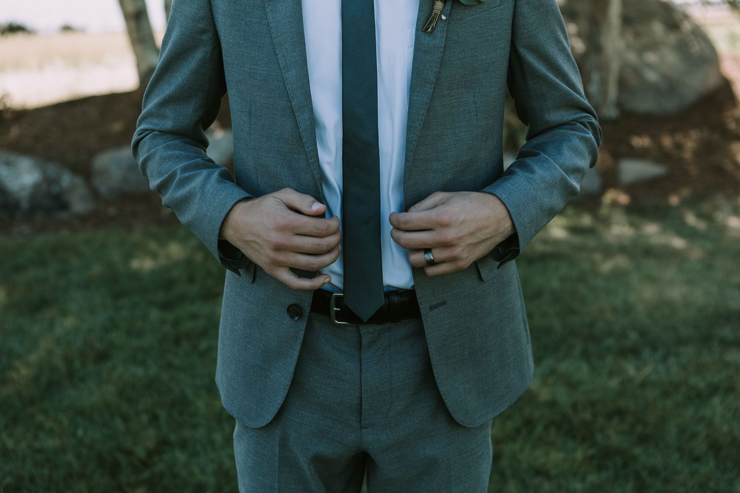Close-up of gray suit jacket with hands adjusting buttons.