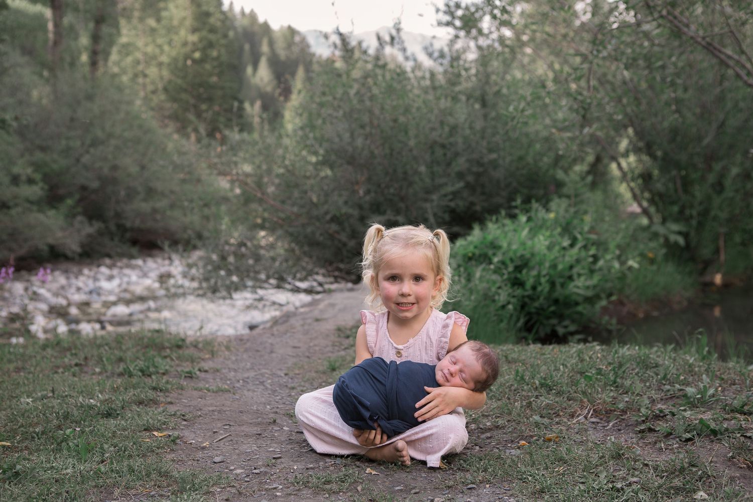 A heartwarming sibling moment captured outdoors by a mountain stream.