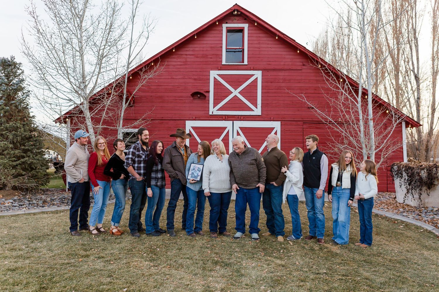 Family members gathered outdoors for a group photo in front of a traditional red barn structure.