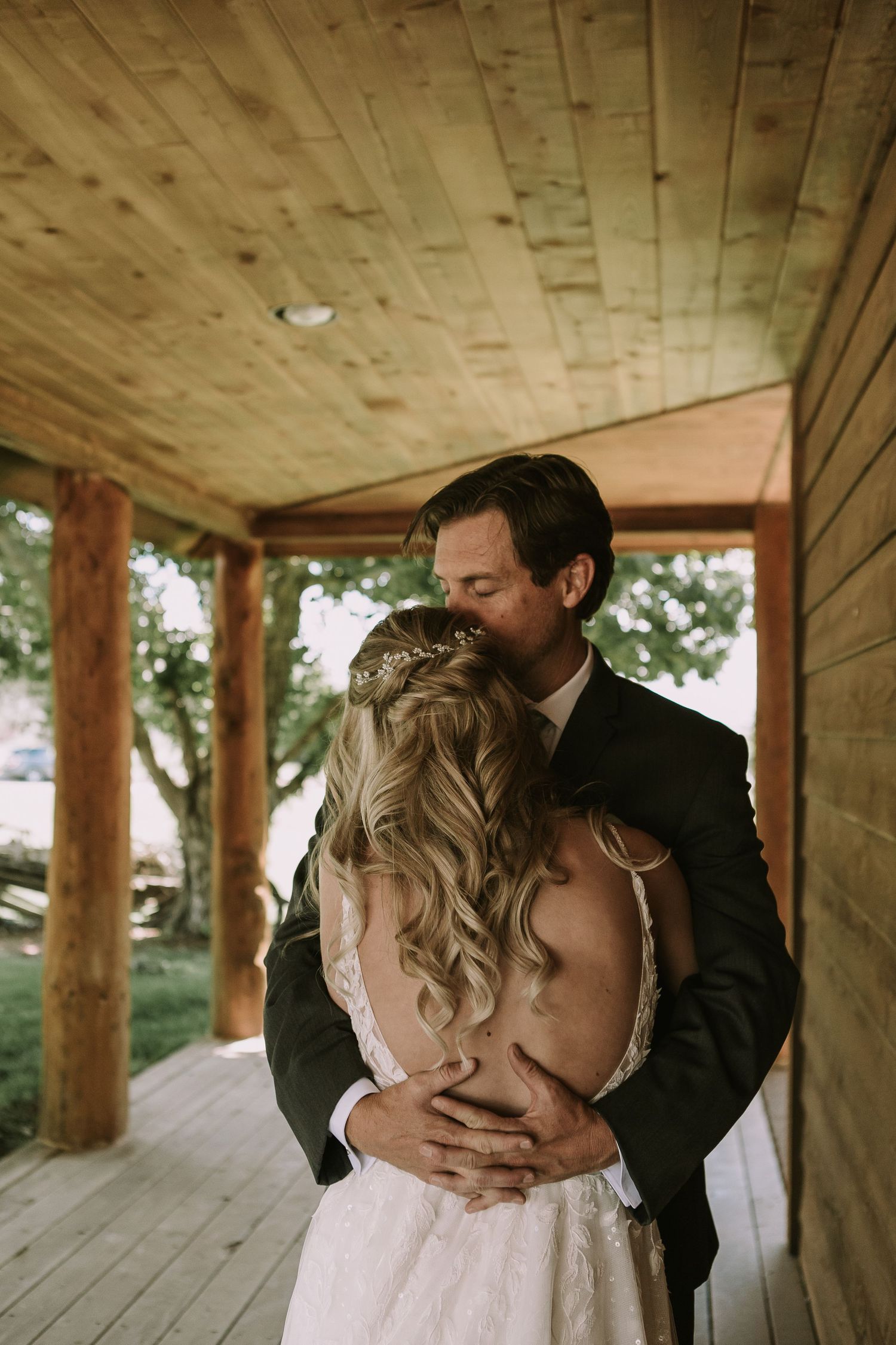 Intimate moment between couple on rustic porch with sunlight filtering through trees.