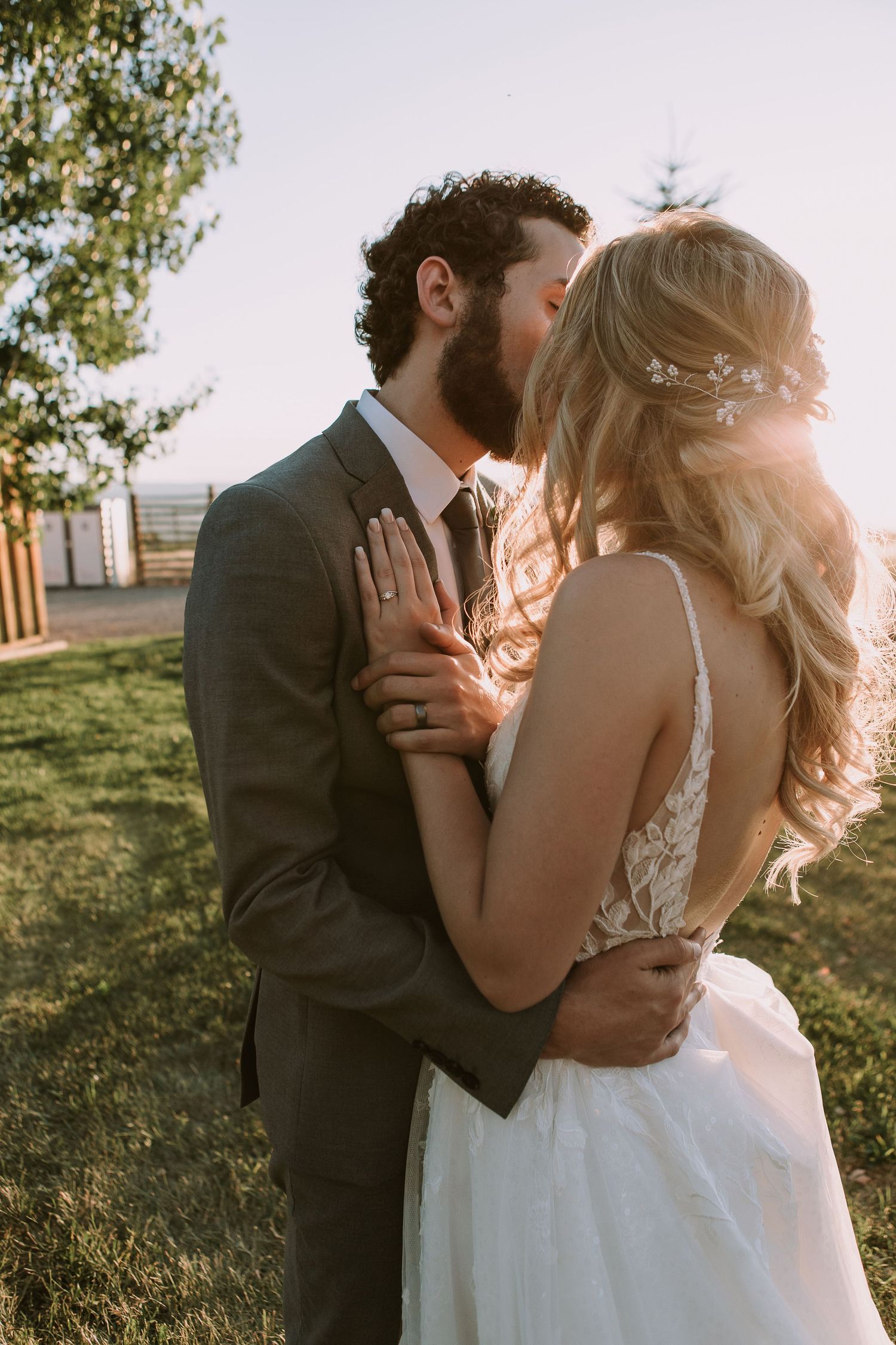 A tender wedding moment captured at sunset with a couple embracing in formal attire.