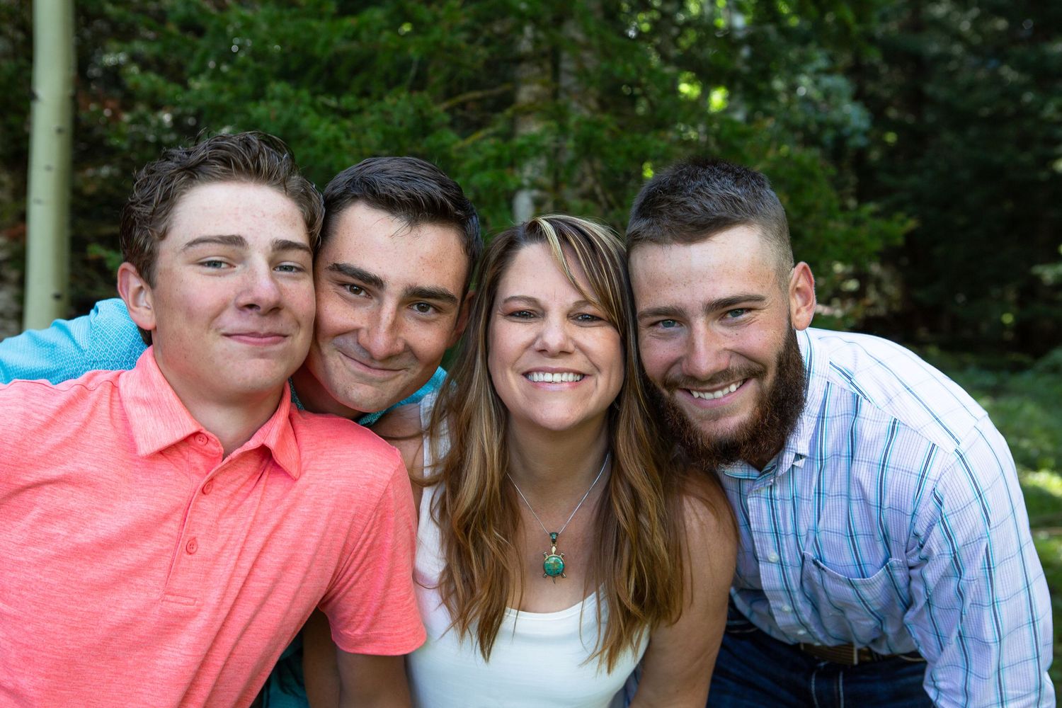 Close group shot of people wearing casual attire against forest background.