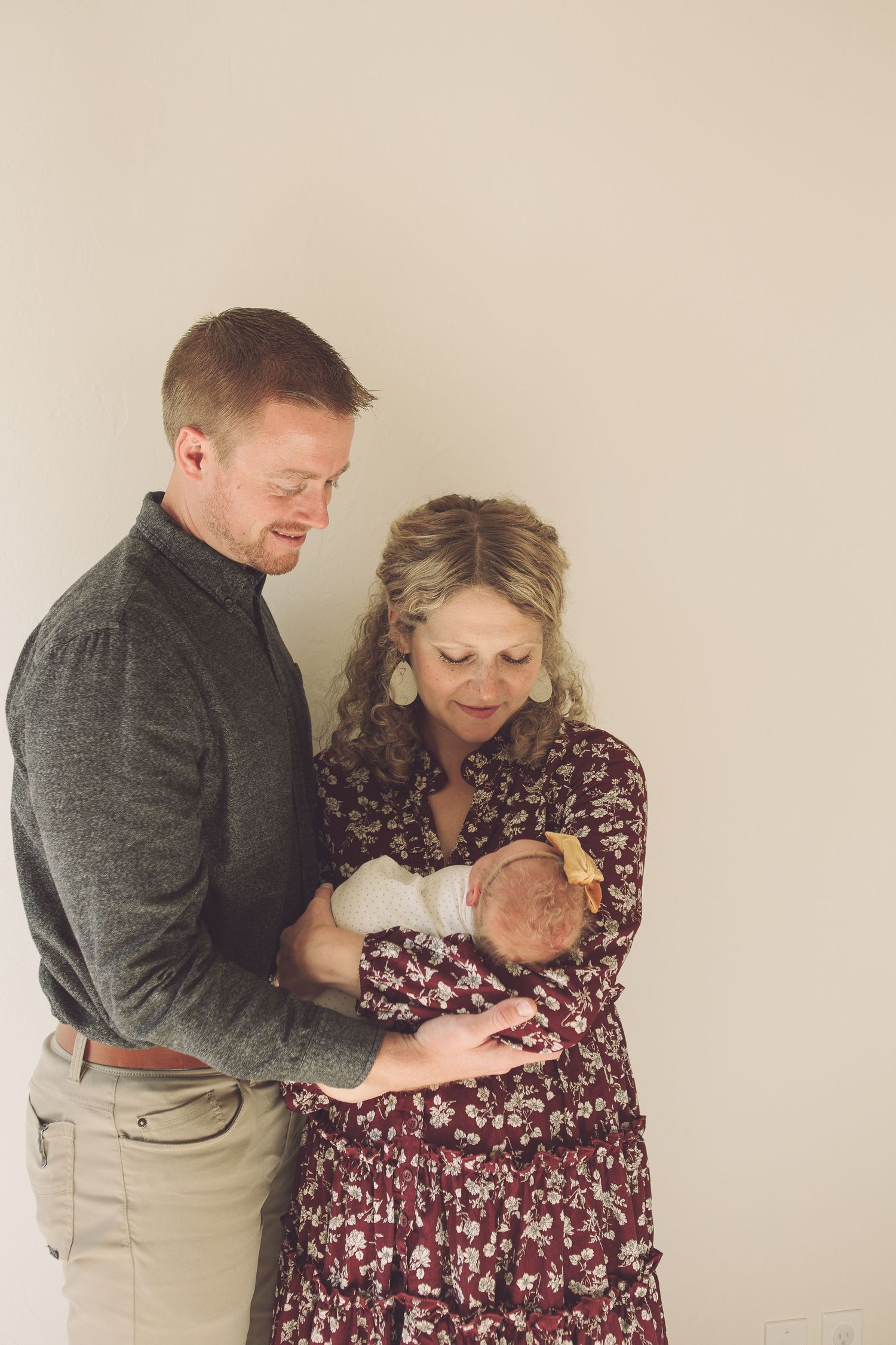 Couple in casual attire sharing intimate moment with newborn baby.