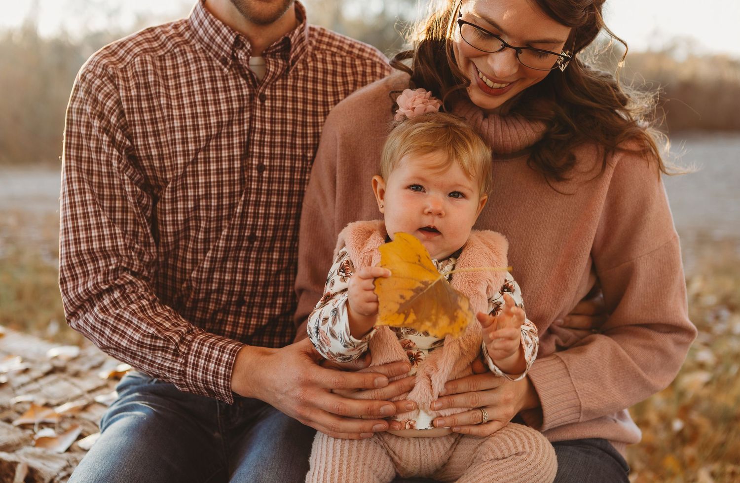 A tender family moment captured while holding a small child with a yellow leaf in autumn.