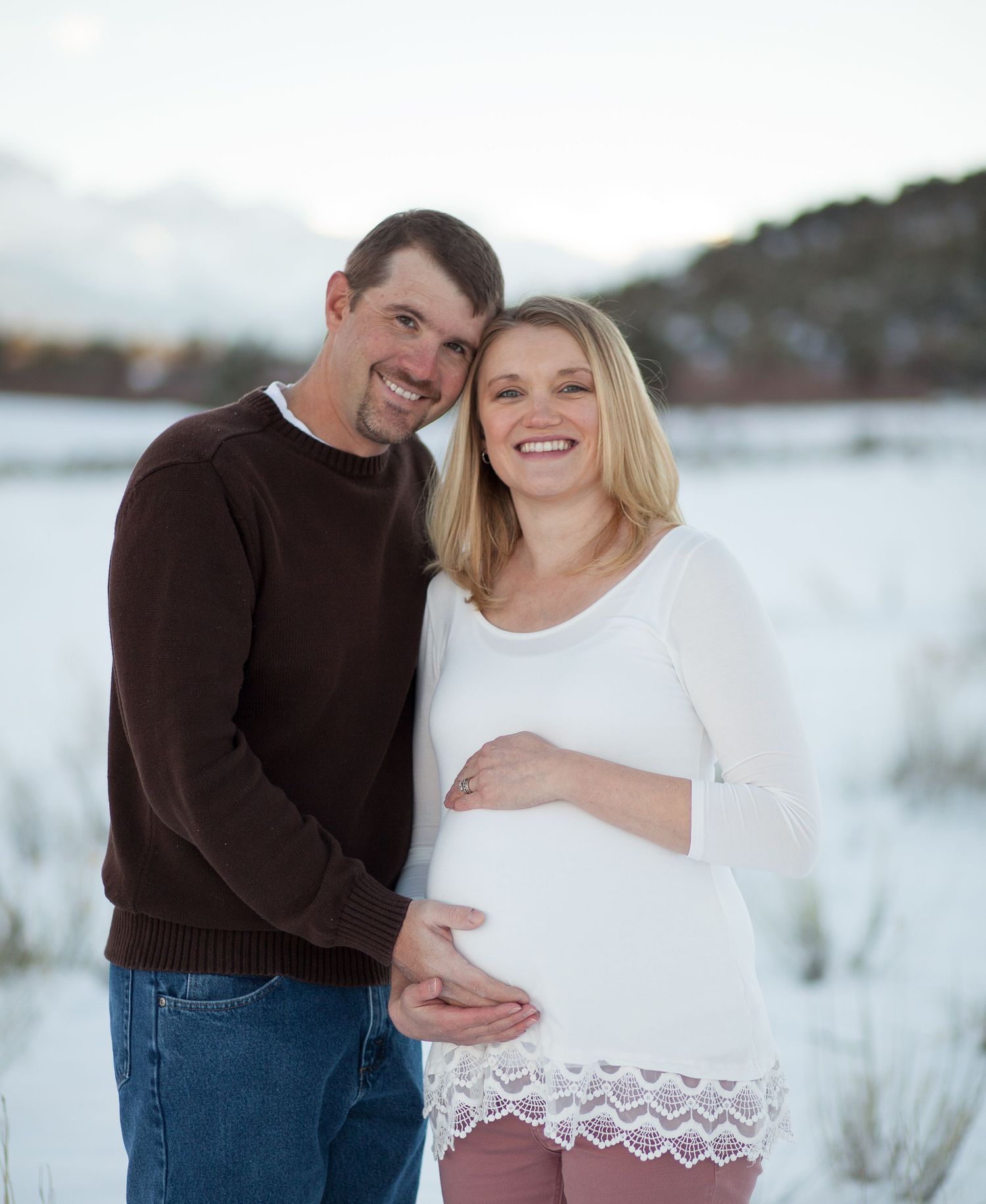 Happy couple sharing intimate moment during winter maternity photoshoot.