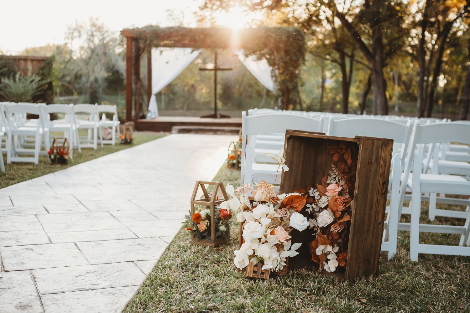 Rustic outdoor wedding ceremony setup with wooden crates and floral decorations at sunset.
