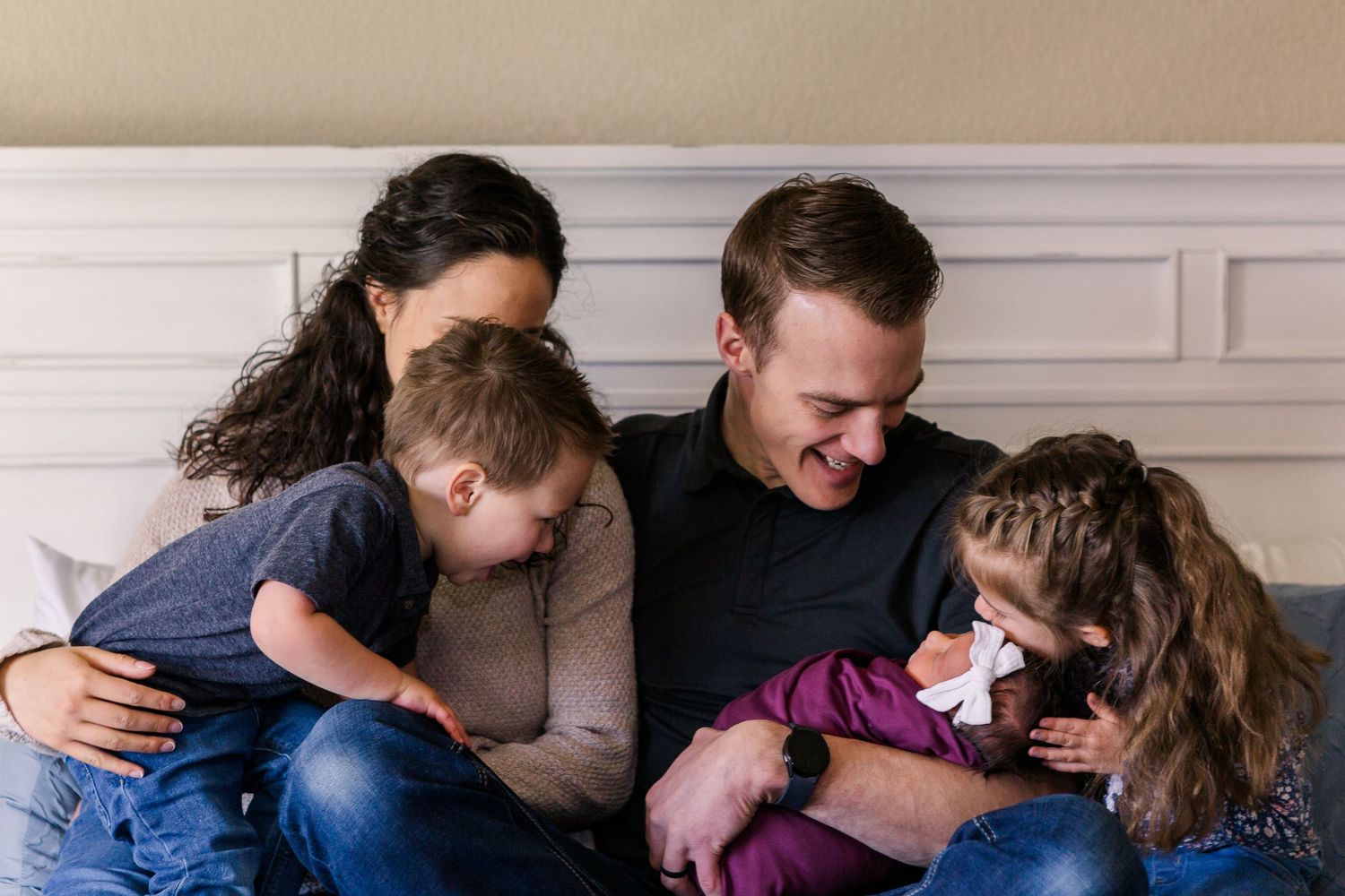 Candid family moment as parents and children share affectionate interaction on couch.