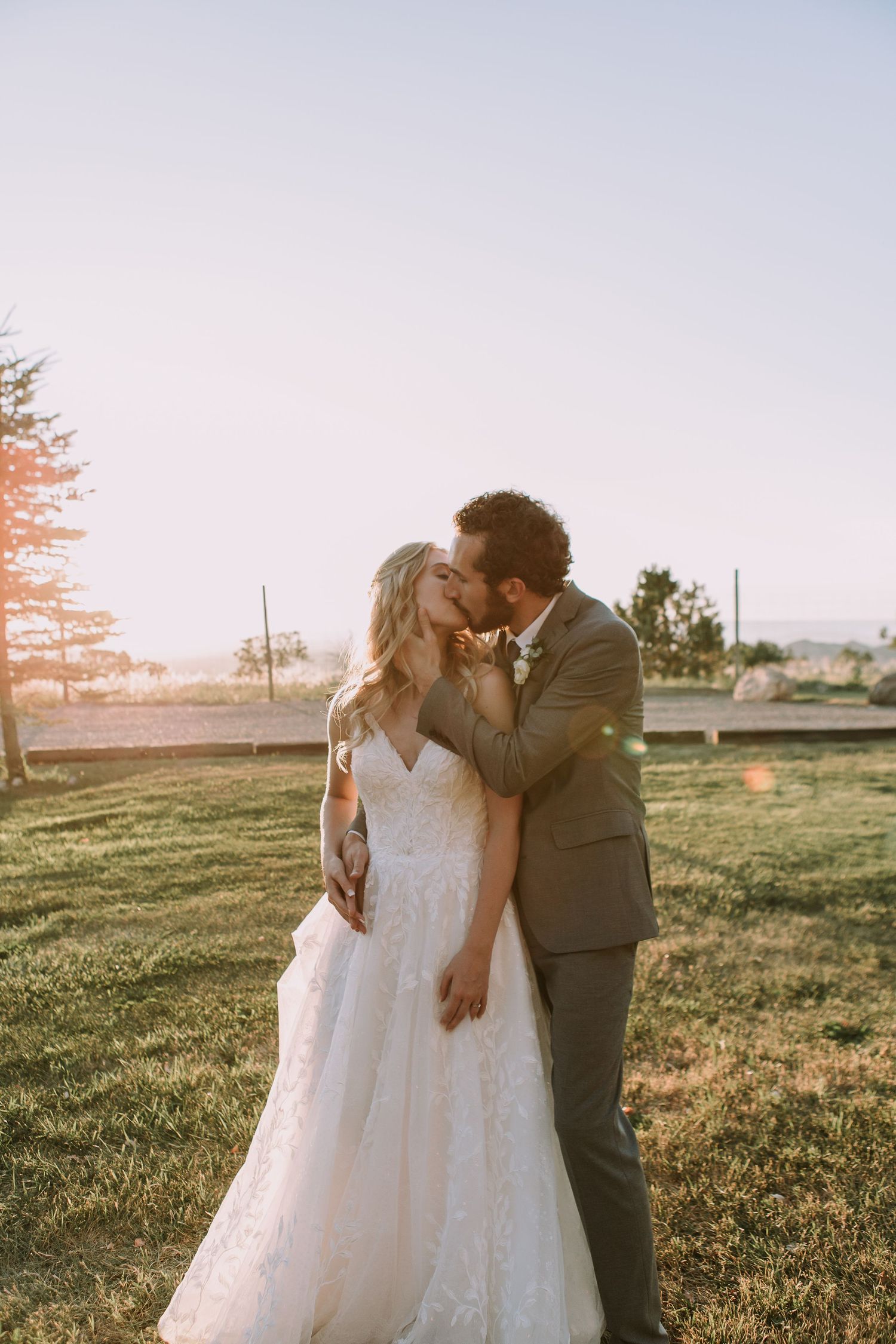 A tender moment between newlyweds as they embrace on their wedding day at sunset.