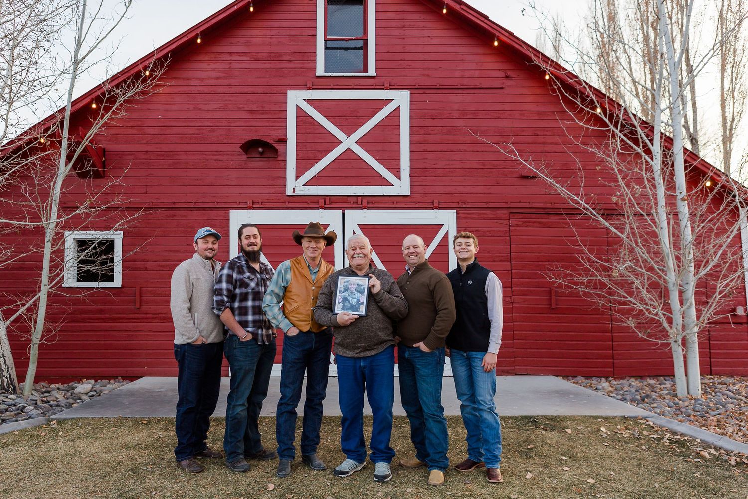 Small group gathered in front of iconic red barn with white X detailing on a winter day.