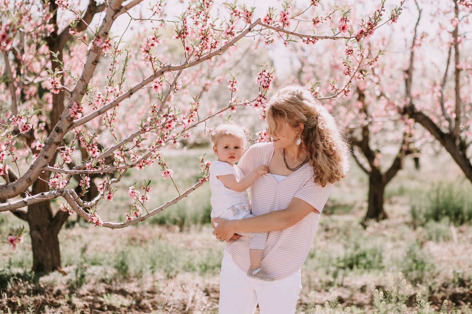 Spring portrait in blooming peach orchard with pink blossoms.