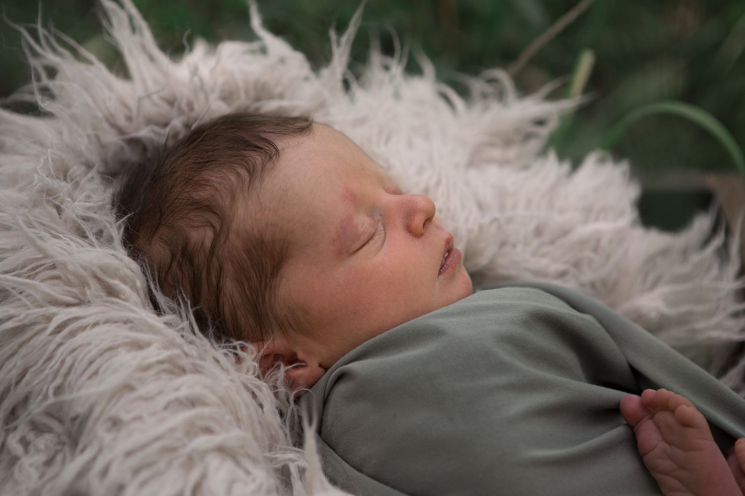 Sleeping newborn resting peacefully on soft white fur material in natural lighting.