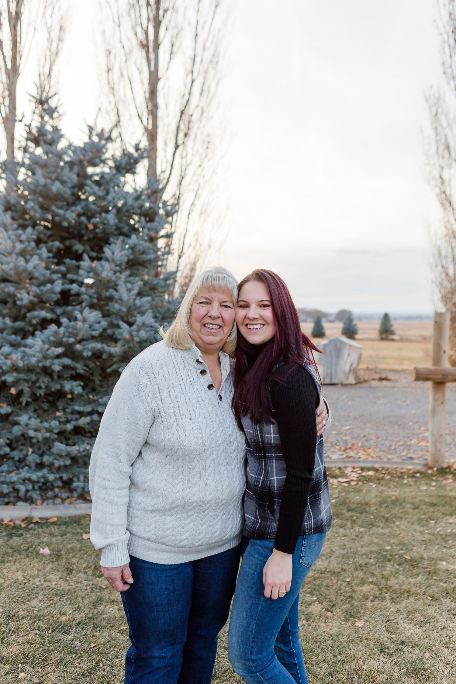 Two people sharing a cheerful moment together outdoors with a blue spruce tree in the background.